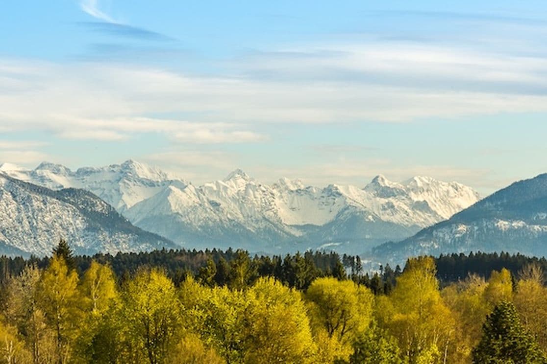 Spring view from Penzberg of snow-capped Alps and green forests – perfect natural setting for residential living and real estate