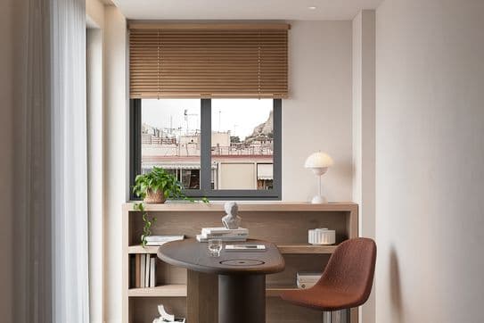 Modern home office with a curved wooden desk, brown chair, and shelves. A window with blinds overlooks a cityscape. Minimalist decor with plants.