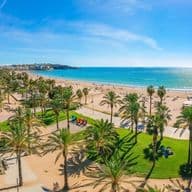 Playa de la Costa Dorada con palmeras, zonas verdes y edificios al fondo