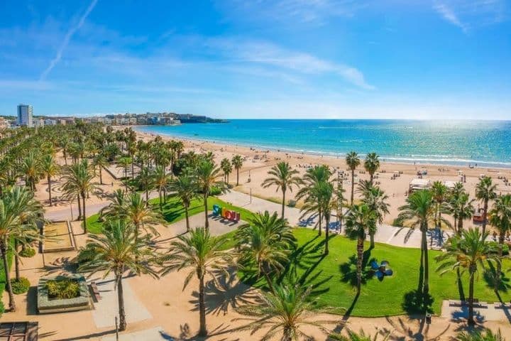 Playa de la Costa Dorada con palmeras, zonas verdes y edificios al fondo