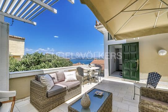 Outdoor patio with wicker furniture, a table, and a view of the ocean under a clear blue sky.