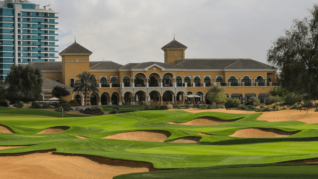 The Spanish-style clubhouse of The Els Club in Dubai Sports City, surrounded by manicured fairways and sand bunkers.