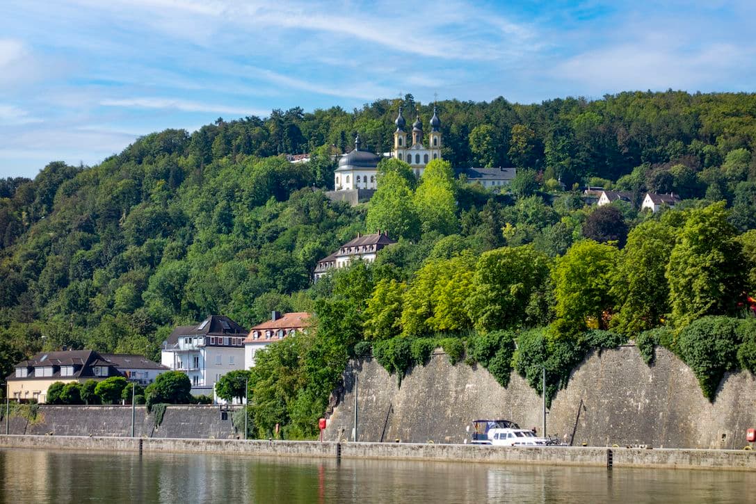 View of the baroque pilgrimage church Käppele on Nikolausberg above the Main river in Würzburg, surrounded by forest and residential houses