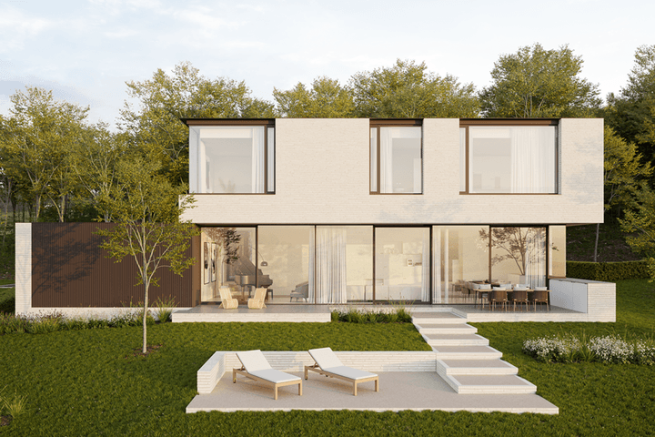 Modern two-story white brick house with large windows, a patio with lounge chairs, and a green lawn. Trees in the background.