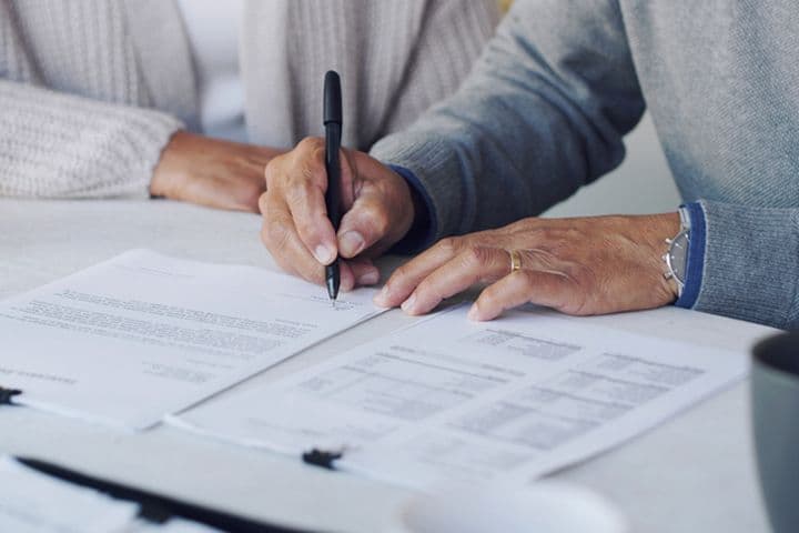 Un couple de personnes âgées signe des documents