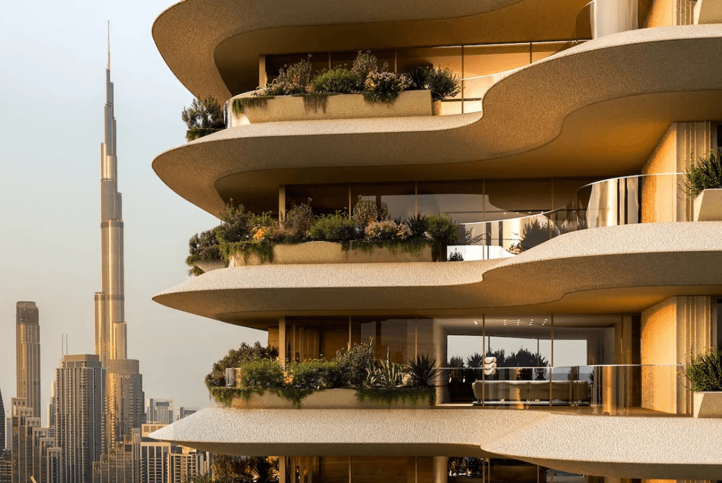 Modern building with curved balconies and lush greenery, set against a city skyline featuring a tall, iconic skyscraper in the background.