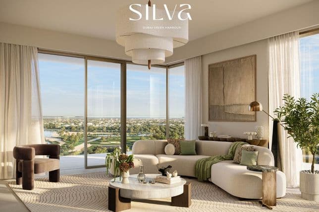 Modernes Wohnzimmer mit großen Fenstern, weißem Ecksofa, Sesseln und einem runden Couchtisch. Darüber befindet sich eine zeitgenössische Leuchte.