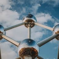 The Atomium in Brussels, Belgium, is a steel structure of nine silver spheres connected by tubes against a blue sky with clouds.