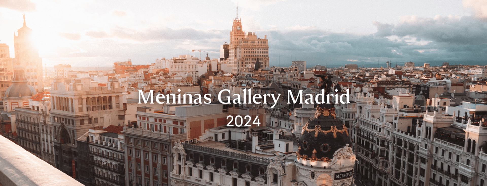 Paisatge urbà de Madrid a la posta de sol, amb edificis històrics, incloent-hi l'edifici Metrópolis amb la seva cúpula ornamentada.