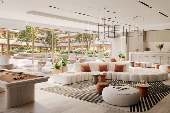 Bright modern hotel lounge with white sofas, orange cushions, a geometric chandelier, and a pool table near glass walls opening to an outdoor courtyard.