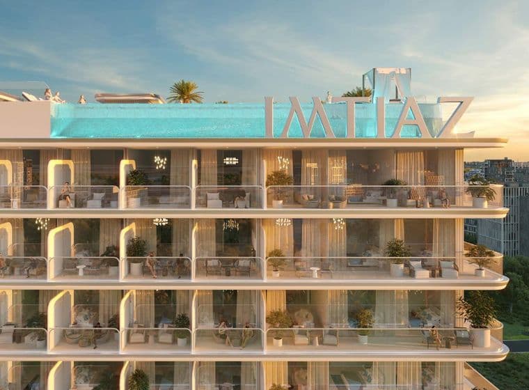 Close-up view of balconies at Cove Edition 6 by Imtiaz Developers in Dubailand, showcasing curved glass railings, outdoor seating, and potted plants.