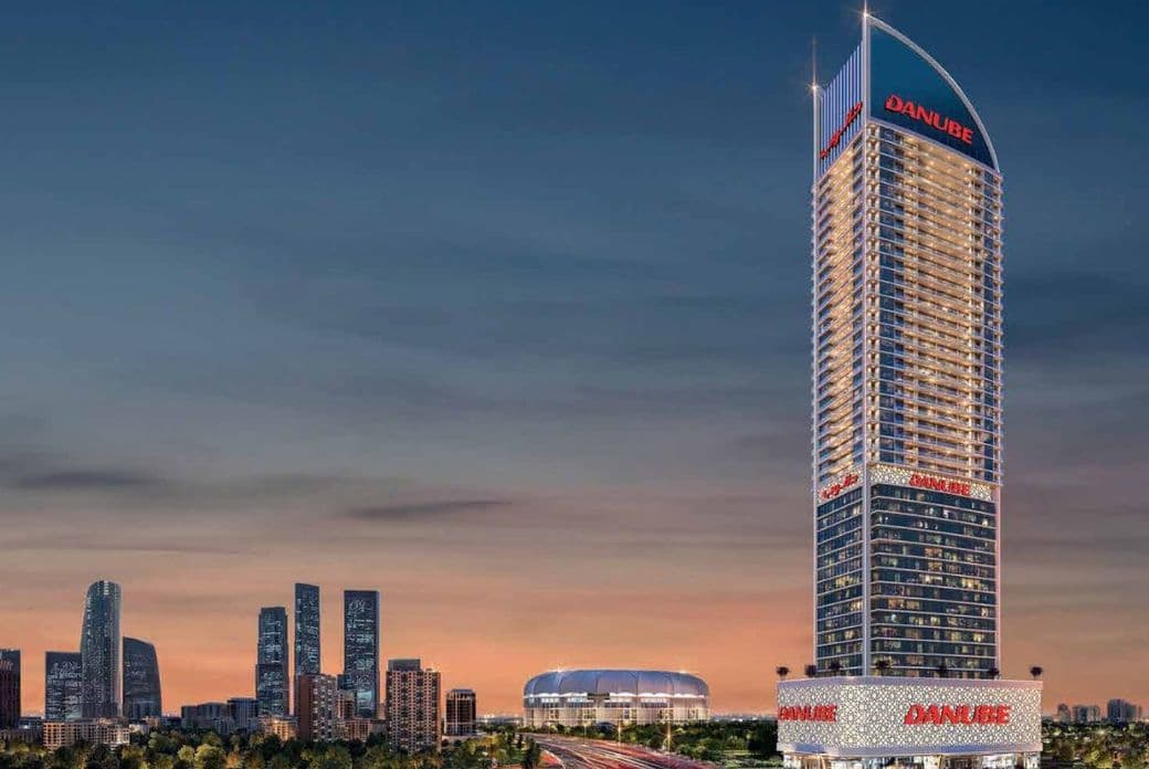 Night view of Danube ASPIRZ iconic tower illuminated in Dubai Sports City by Danube Properties, with surrounding cityscape and roads