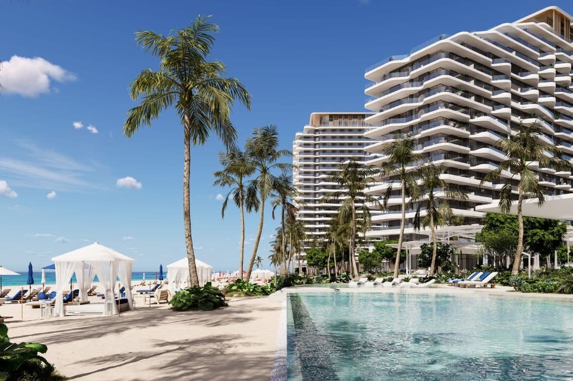 Luxury beachfront pool and private cabanas at Nikki Beach Residences by Aldar in RAK, set against a backdrop of swaying palms and ocean.