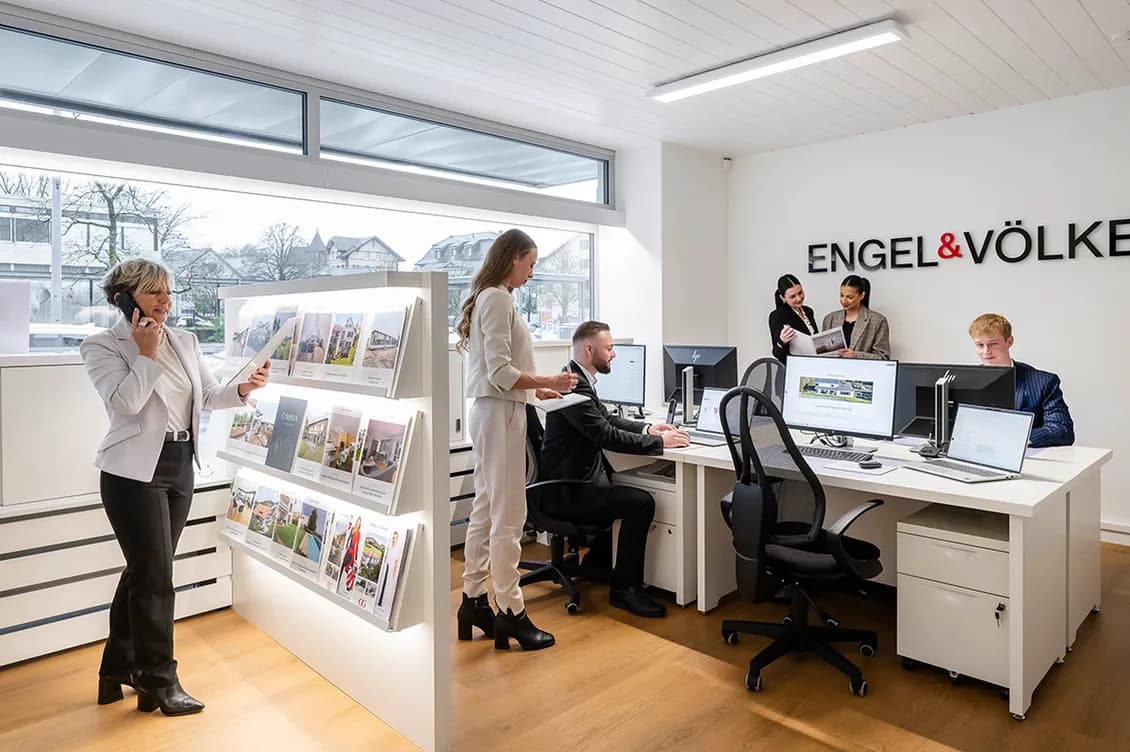 Immobilienberater:innen von Engel & Völkers Uster beraten Kund:innen in einem modernen, offenen Büro.