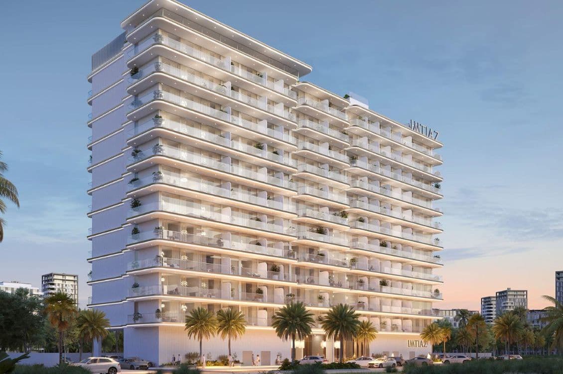 exterior view of Cove Edition 6 by Imtiaz Developers in Dubailand, featuring a sleek white façade with curved balconies and palm trees.