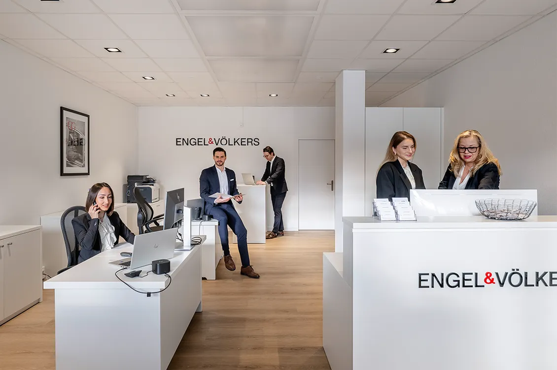 Immobilienberater:innen von Engel & Völkers Küsnacht beraten Kund:innen in einem modernen, offenen Büro.