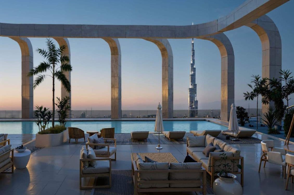 Luxuriöse Dachterrasse mit modernen Möbeln, Pool und hohen Bögen mit Blick auf eine Stadtsilhouette bei Sonnenuntergang, in der ein markanter Wolkenkratzer hervorsticht.