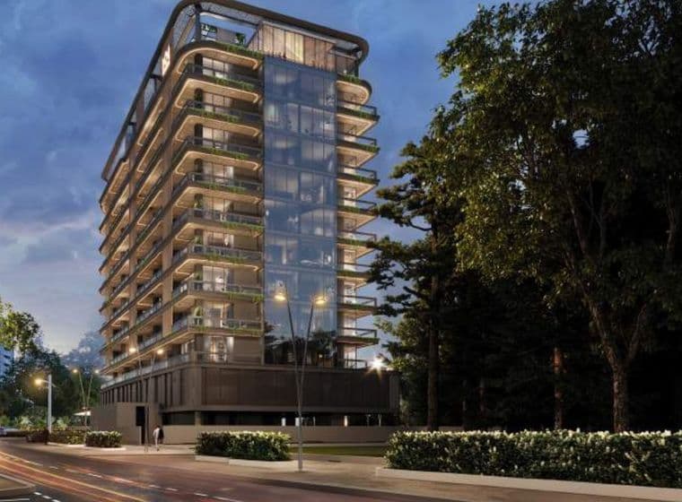 Evening exterior view of Marquis Vista at DLRC by Marquis Development, showcasing the modern glass façade, wraparound balconies, and illuminated architecture surrounded by greenery.