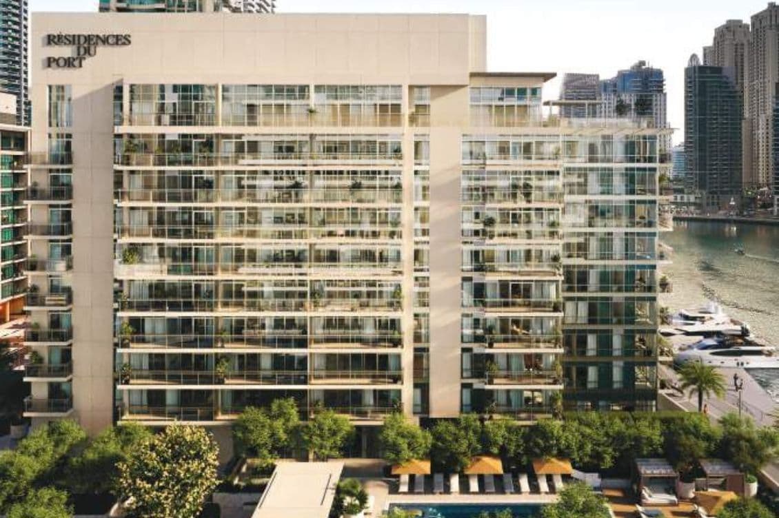 Full building view of Residences Du Port with marina-front setting, lush landscaping, and outdoor pool area in Dubai Marina.
