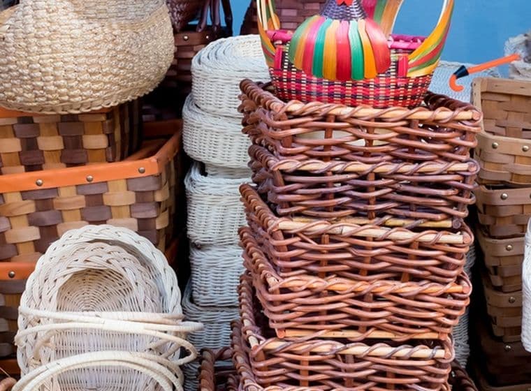 Sortierte gewebte Körbe in verschiedenen Formen und Farben, gestapelt in einer Ausstellung, darunter Korbgeflecht- und Strohdesigns mit farbenfrohen Akzenten.