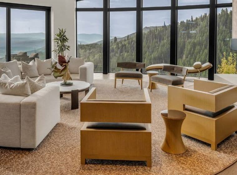 Geräumiges Wohnzimmer mit modernen Möbeln, großen Fenstern mit Blick auf die Berge und einem Kamin auf der rechten Seite.