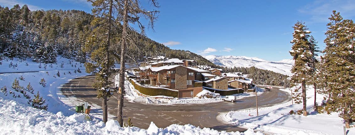 Komplex von Apartments in Masella, umgeben von Schnee, Bäumen und Bergen.