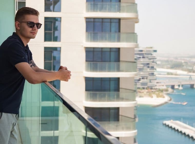 Mann steht auf dem Balkon einer kurzfristig vermieteten Immobilie mit Blick auf den Jachthafen und die Yachten von Dubai