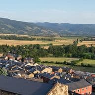 Església de Llívia en primer pla, seguida de cases, camps i muntanyes.