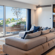 Modern living room with large glass doors, sea view, and elegant minimalist design