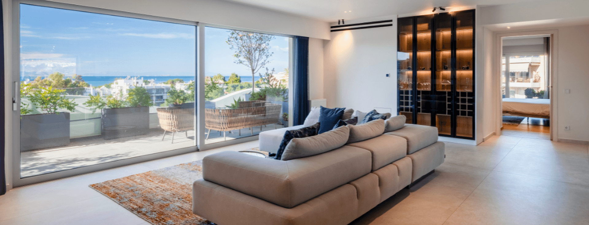 Modern living room with large glass doors, sea view, and elegant minimalist design