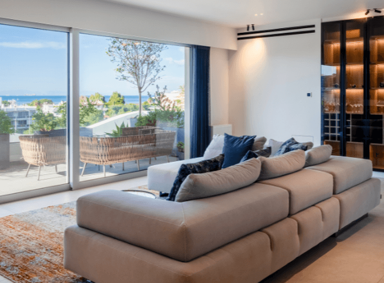 Modern living room with large glass doors, sea view, and elegant minimalist design