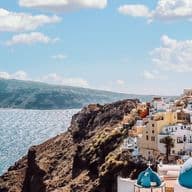 Panoramic view of Santorini with whitewashed buildings, blue-domed churches, and the Aegean Sea.