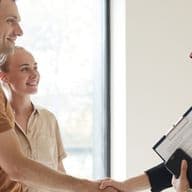 Conveyancing professional shakes hands with couple after agreeing fees and processes to transfer property ownership