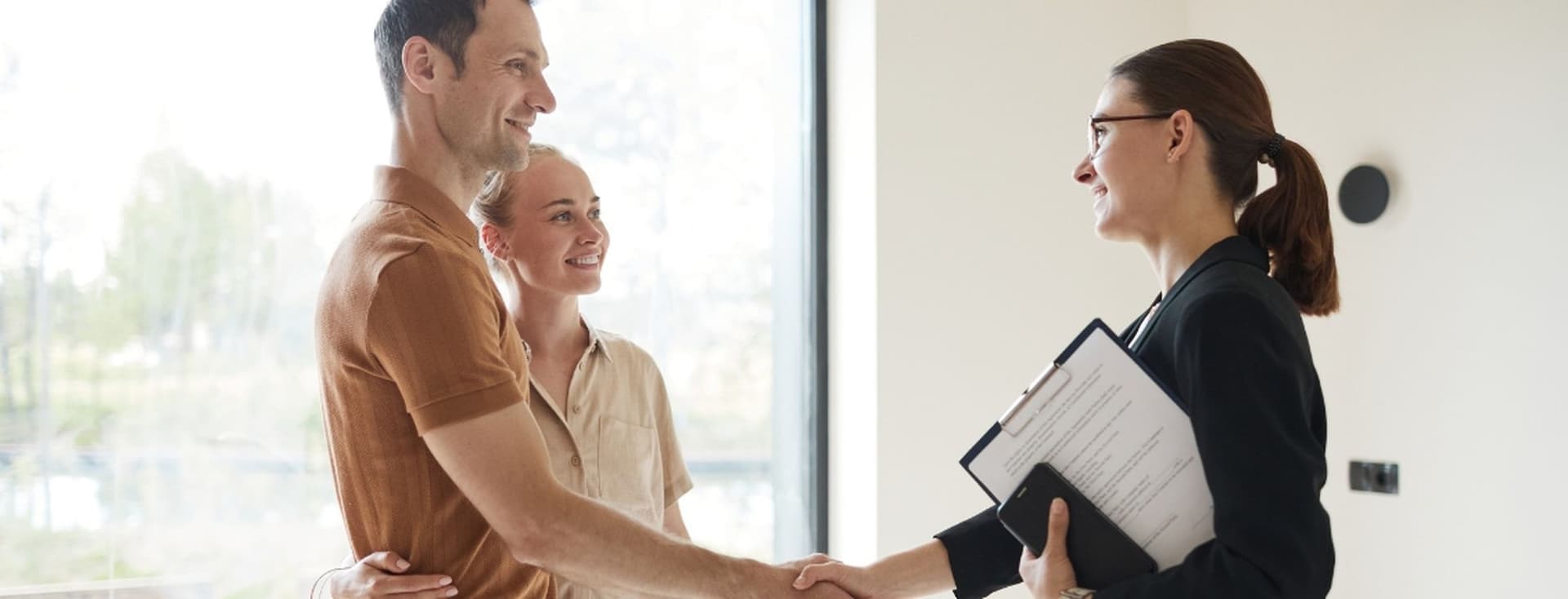 Conveyancing professional shakes hands with couple after agreeing fees and processes to transfer property ownership
