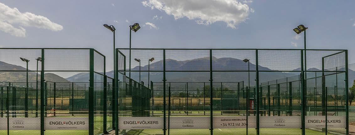 Pistes de pàdel rotulades amb el logo d'Engel&Völkers i la muntanya La Tosa al darrere.