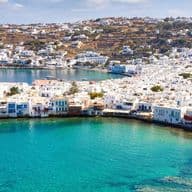 Πανοραμική θέα παραθαλάσσιας πόλης με λευκά σπίτια, τιρκουάζ νερά και γραφικό λιμάνι