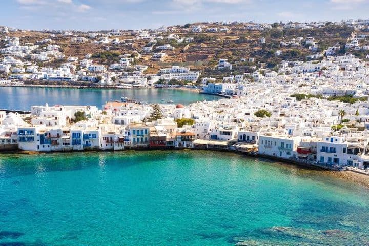 Πανοραμική θέα παραθαλάσσιας πόλης με λευκά σπίτια, τιρκουάζ νερά και γραφικό λιμάνι