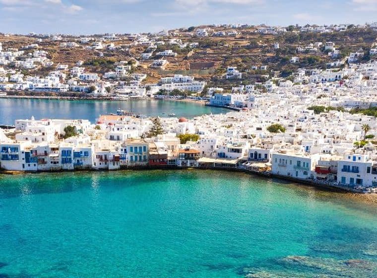 Πανοραμική θέα παραθαλάσσιας πόλης με λευκά σπίτια, τιρκουάζ νερά και γραφικό λιμάνι