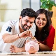 Glückliches Paar legt Geld in ein Sparschwein und spart eifrig für eine Hypothekeneinlage in Dubai