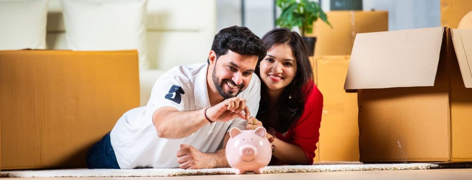 Glückliches Paar legt Geld in ein Sparschwein und spart eifrig für eine Hypothekeneinlage in Dubai