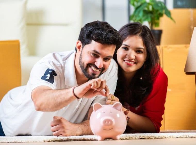 Glückliches Paar legt Geld in ein Sparschwein und spart eifrig für eine Hypothekeneinlage in Dubai
