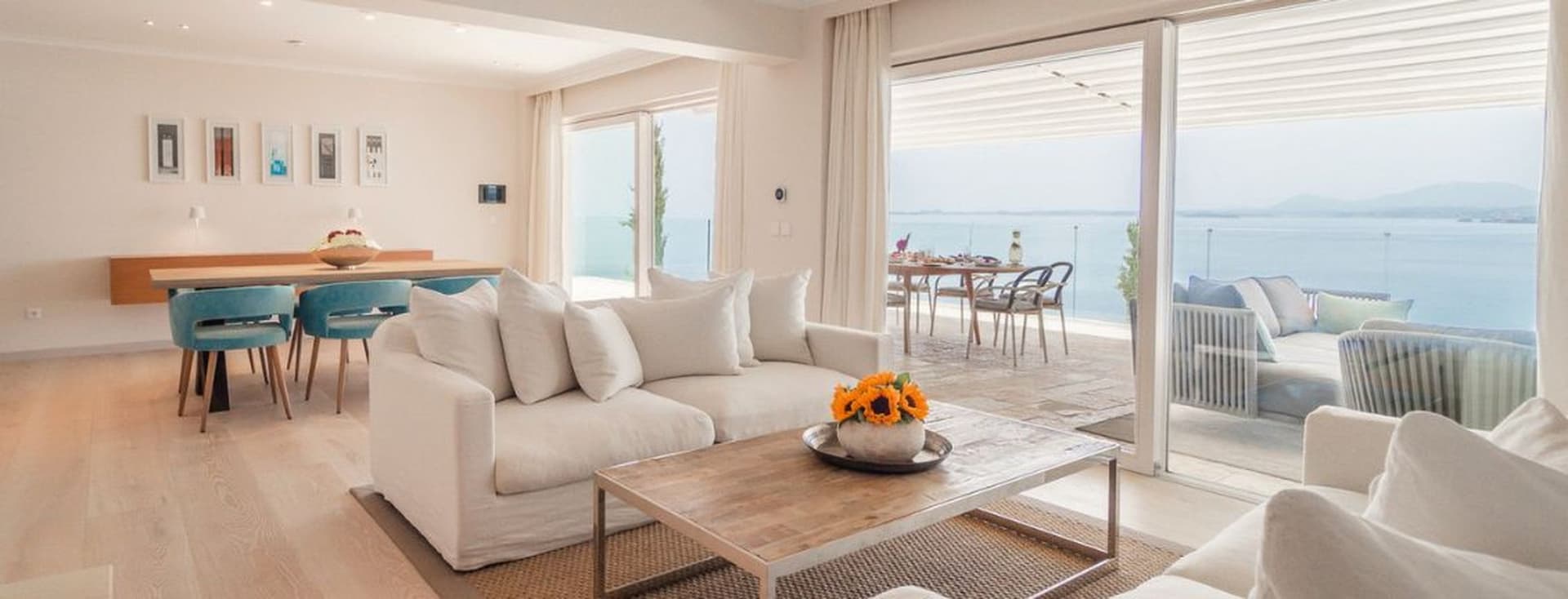 Bright open-plan living room with elegant contemporary furnishings, floor-to-ceiling sliding doors, and panoramic sea views