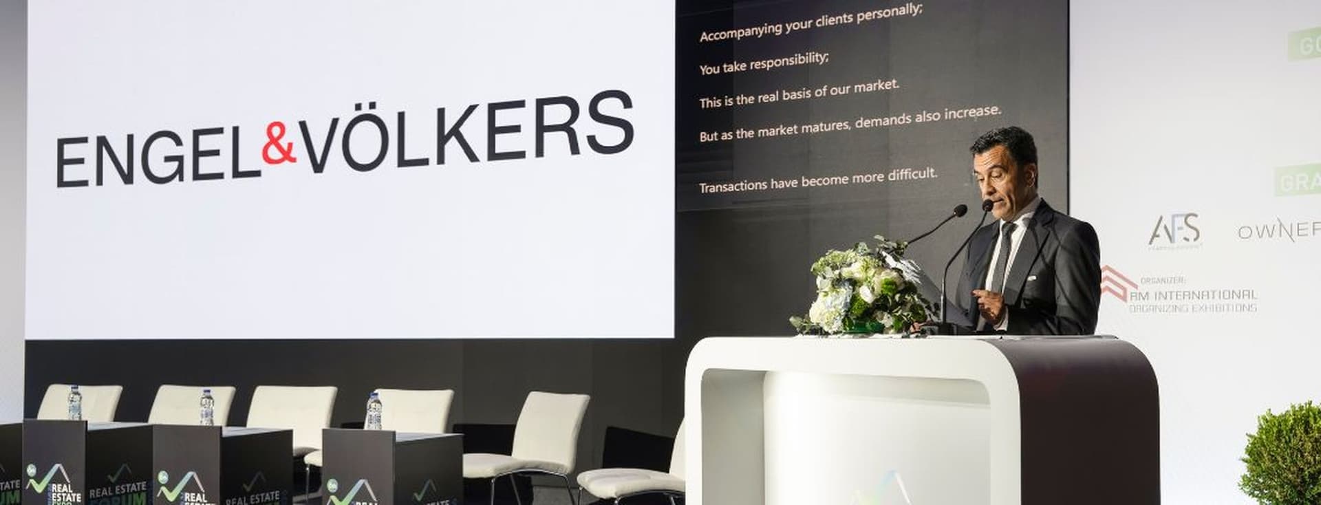 Speaker presenting at the Real Estate Forum conference with Engel & Völkers branding on stage