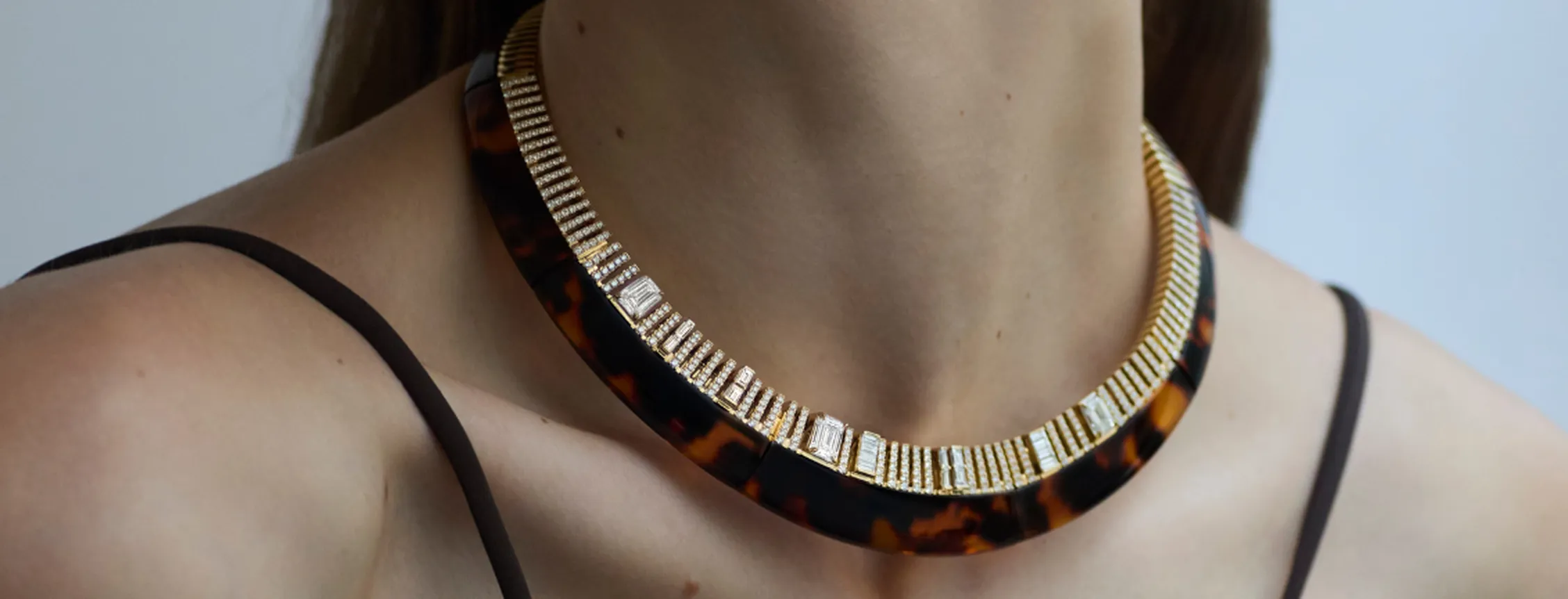 Close-up of a woman wearing a statement tortoiseshell choker necklace embellished with diamonds and gold.
