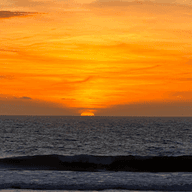 Posta de sol a Tarifa. Cel ataronjat i el sol ponent-se a l'horitzó.