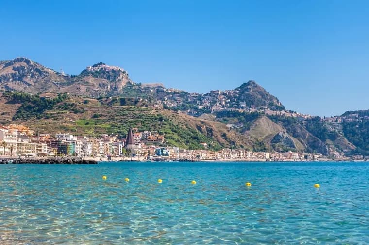Scenic coastal town with clear turquoise waters and mountains rising in the background