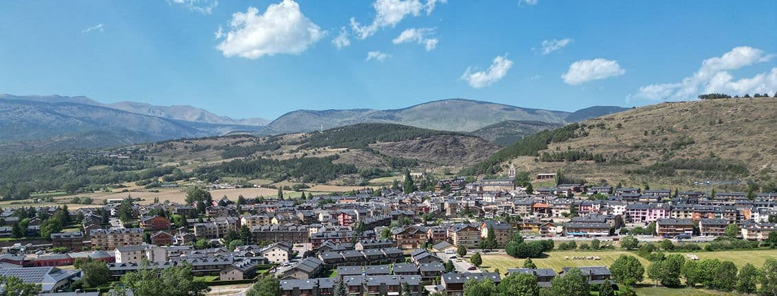 Vista de les cases del poble de Llìvia amb muntanyes al fons.