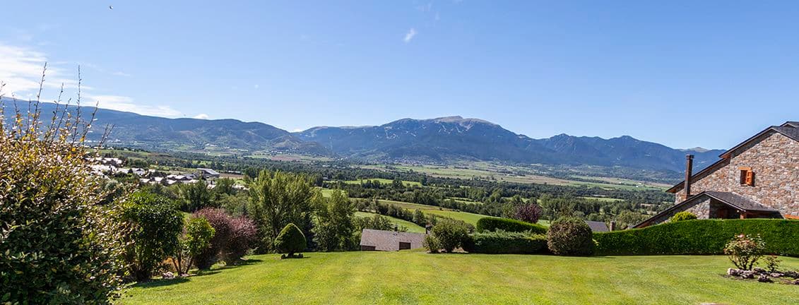 Jardí amb gespa verda i vistes a la vall i muntanyes.