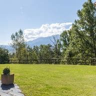 Porxo amb tumbona, arbre amb fulles tardorenques i jardí.