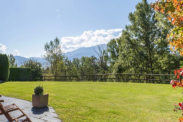 Porxo amb tumbona, arbre amb fulles tardorenques i jardí.